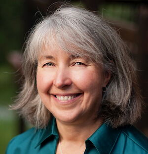Dr. Karen Wyatt, smiling, with gray hair and wearing a teal collared shirt