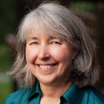 Dr. Karen Wyatt, smiling, with gray hair and wearing a teal collared shirt