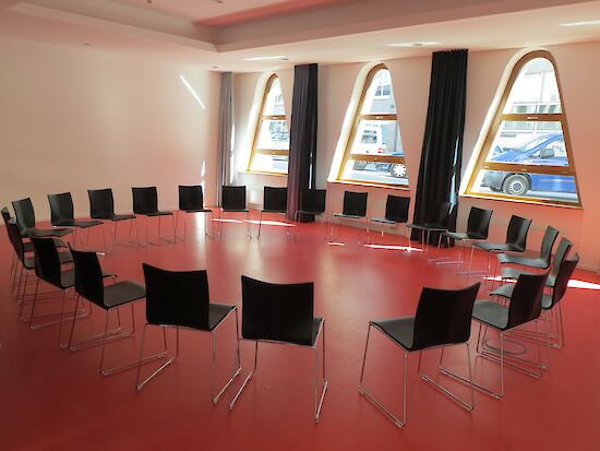 An empty meeting room with chairs arranged in a large circle, ready for a support group