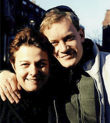 Emma and her husband Barry, smiling outdoors with their arms around each other in Boston