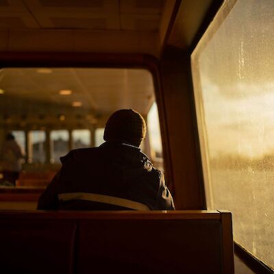 A person sitting alone on the edge of a bed in the morning light, reflecting on the grief of losing a spouse.