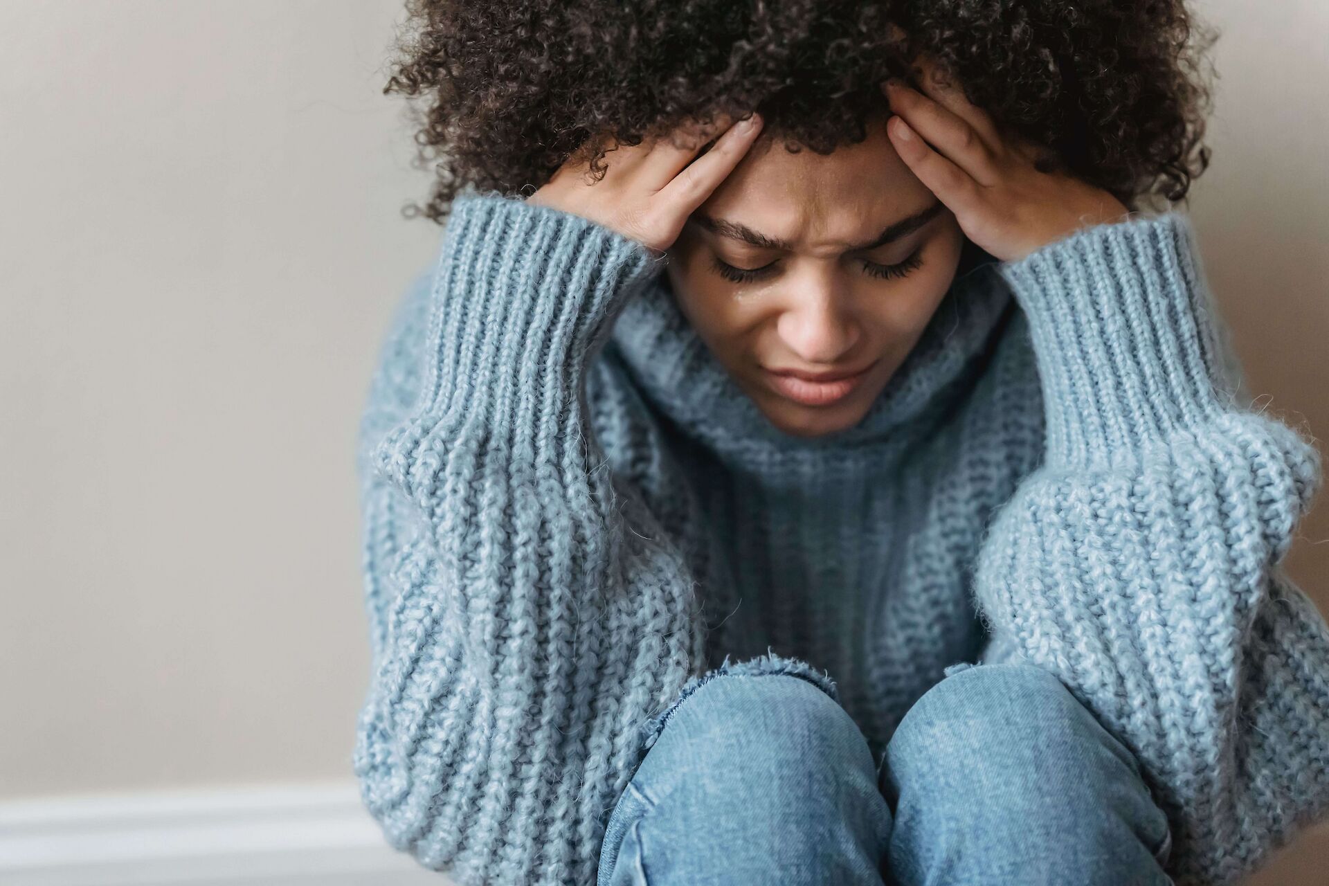Close up of an exhausted caregiver resting their face in their hands, representing caregiving burnout and cancer loss.