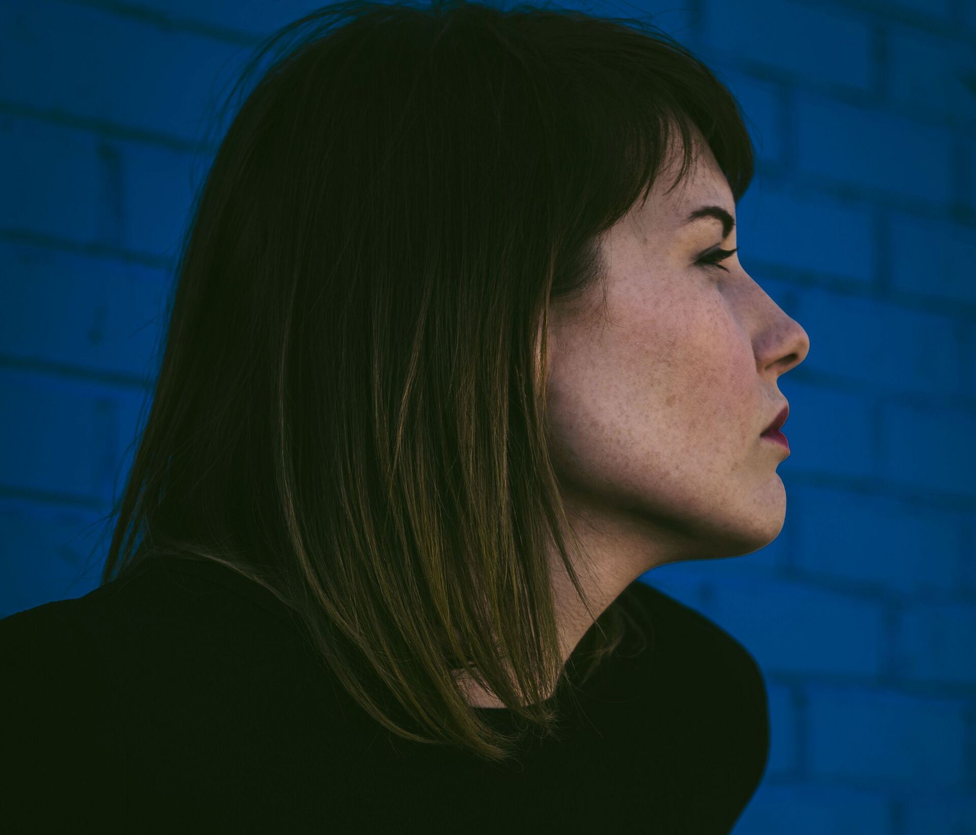 Close up of an exhausted caregiver resting their face in their hands, representing caregiving burnout and cancer loss.