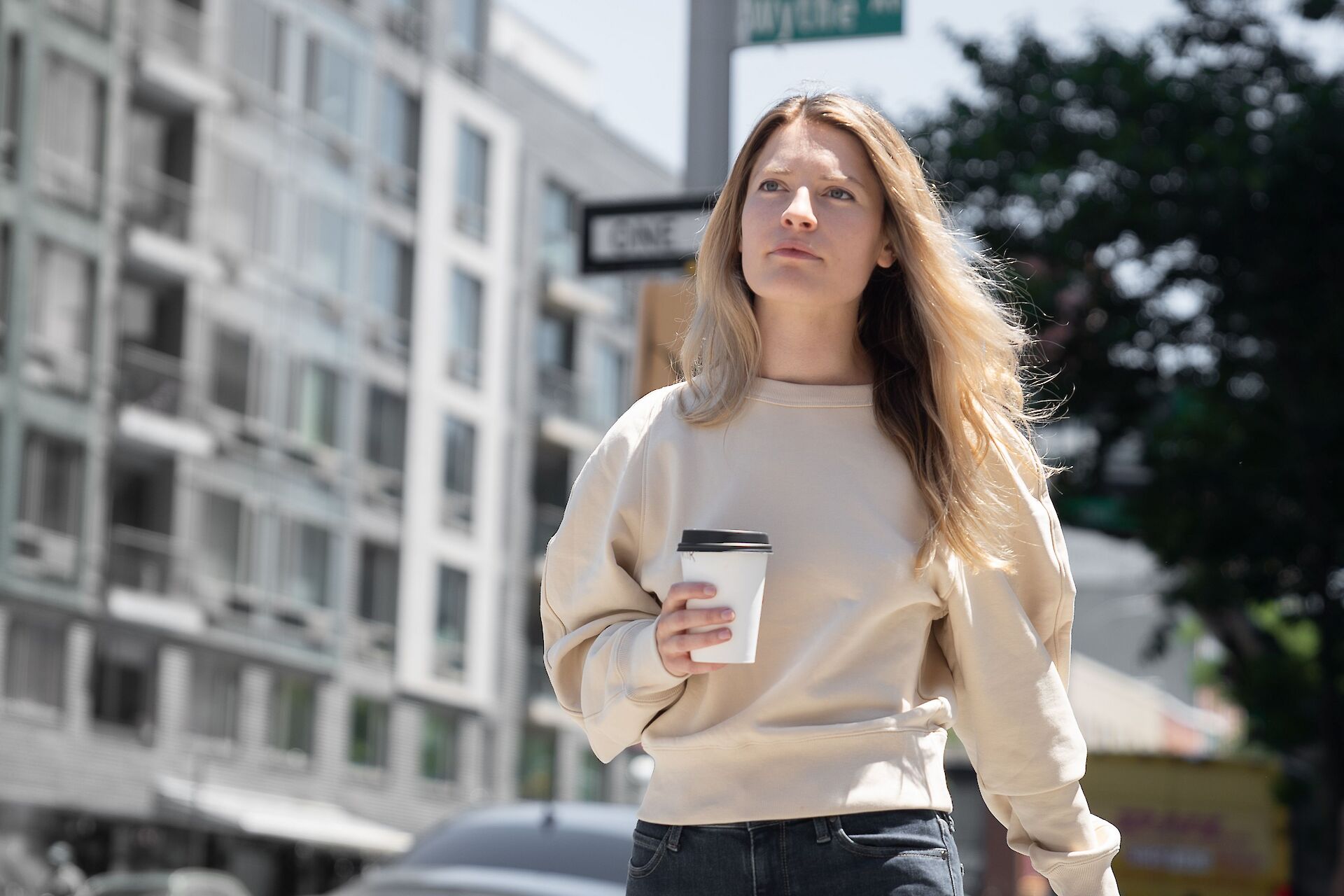 An adult woman looking thoughtfully out the window with a coffee, navigating the grief of losing her mom as an adult.