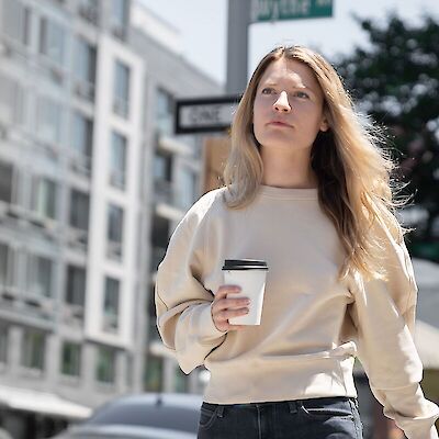 An adult woman looking thoughtfully out the window with a coffee, navigating the grief of losing her mom as an adult.