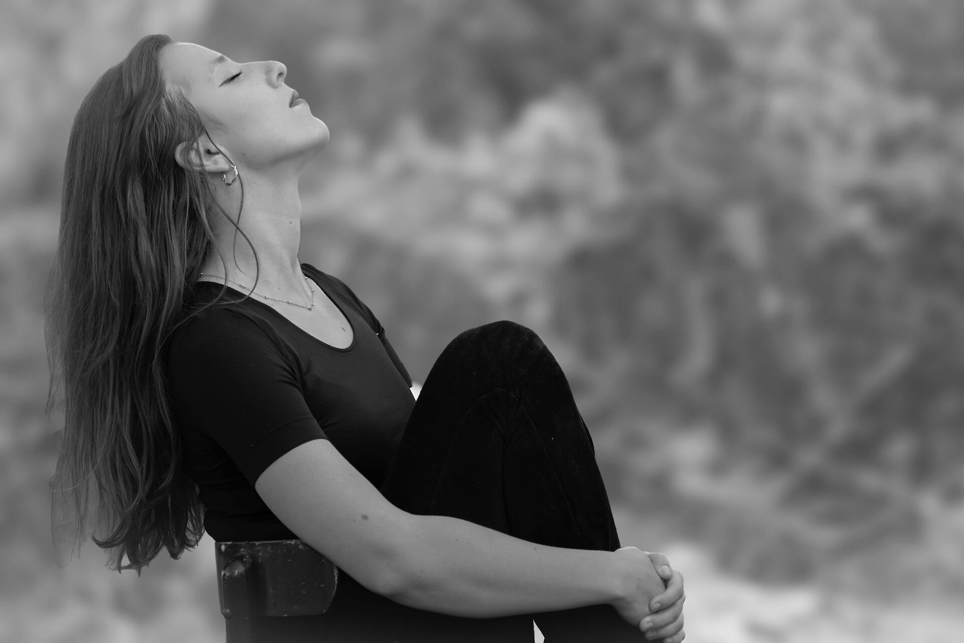 Woman sitting in nature with eyes close taking in nature
