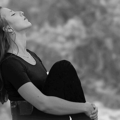 Woman sitting in nature with eyes close taking in nature
