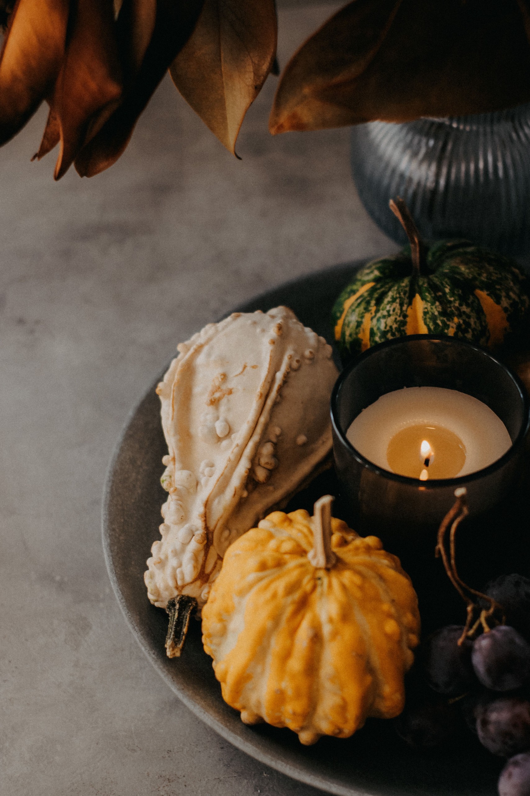 candle lit in a decorative bowl with thanksgiving squashes